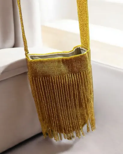 Mochila tejida en mostacillas. Diseño dorado con flecos